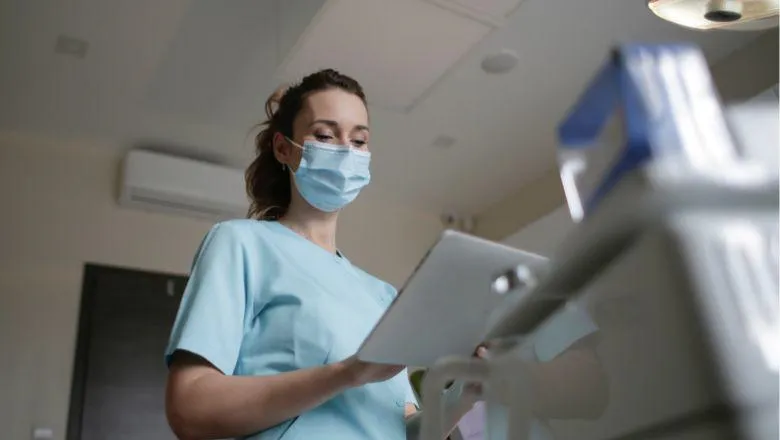 Nurse with a clipboard by equipment